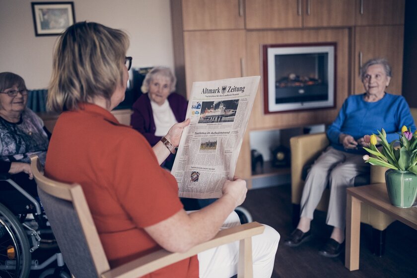 Eine Mitarbeiterin liest täglich eine Zeitung mit den Bewohnern