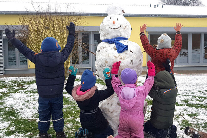Kinder der Notbetreuung präsentieren ihren selbstgebauten Schneemann. 