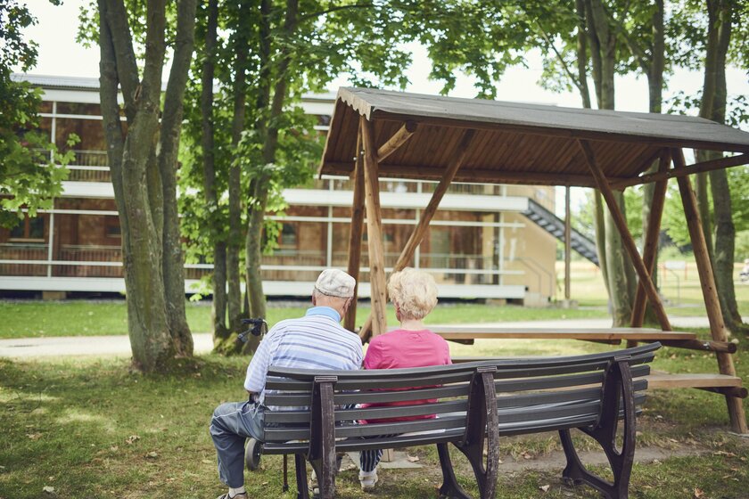 Zwei Bewohner sitzen im Park der Senioren-Wohnanlage