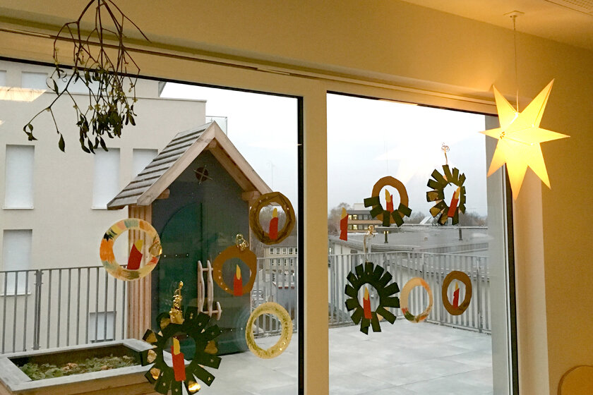 Selbstgebastelte kleine Adventskränze aus Tonkarton dekorieren die Fensterscheiben der Kita.