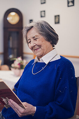 Eine Bewohnerin in blauem Pullover liest