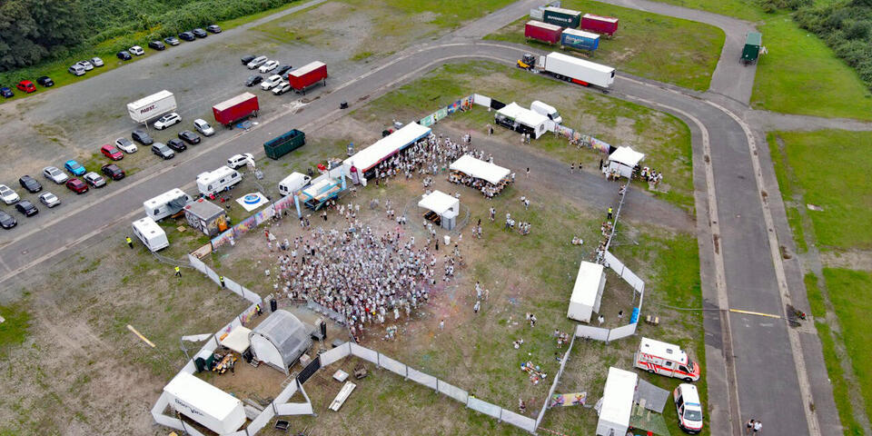 Ein Festivalgelände mit Menschen von oben mit Einsatzwagen der Johanniter
