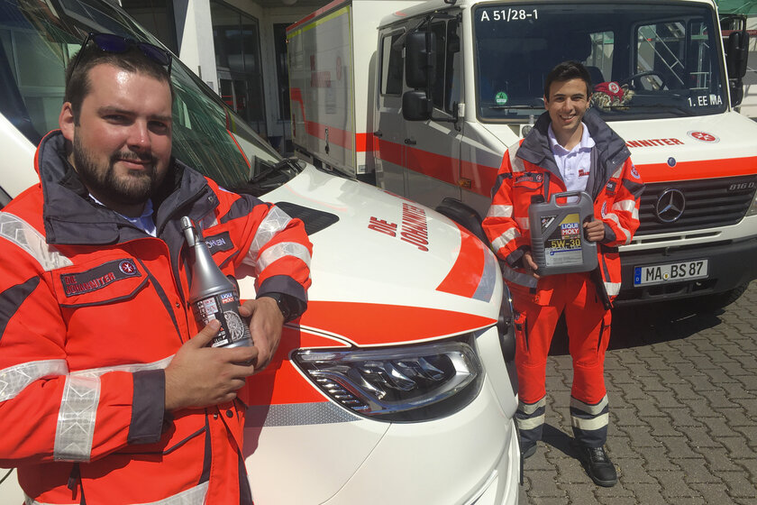 Zwei Rettungskräfte halten gespendete Motoröle und Autopflegemittel des Unternehmens Liqui Moly in der Hand.