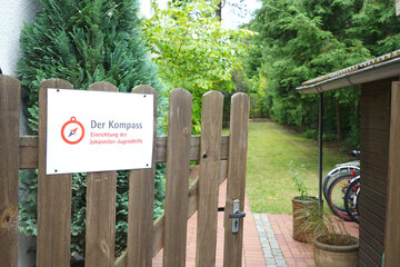 geöffnetes Gartentor mit Schild "Johanniter-Jugendhilfe Kompass"