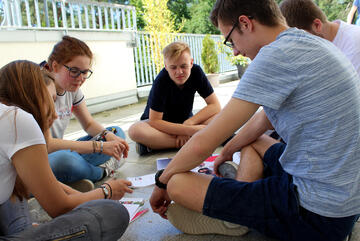 Eine Gruppe Jugendliche sitzt im Kreis und unterhält sich über Mitschriften