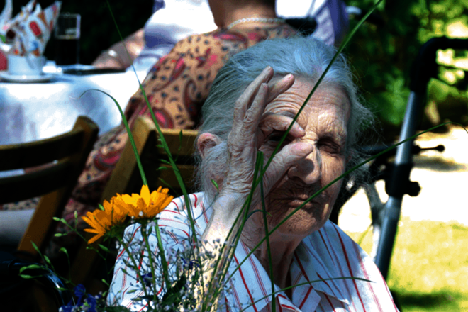 Ein älterer Herr und eine ältere Dame vor Blumenschmuck im Garten