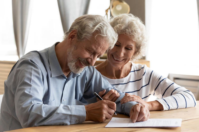 Älteres Ehepaar unterschreibt Unterlagen.