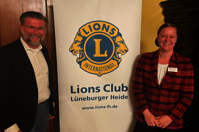 ein Mann und ein Frau stehen rechts und links von einem weißen Rollup mit der Aufschrift "Lions Club Lüneburger Heide" und dem Logo des Lions Club
