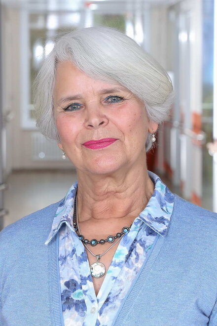 Weißhaarige ältere Dame mit hellblauer Kleidung in Krankenhausflur
