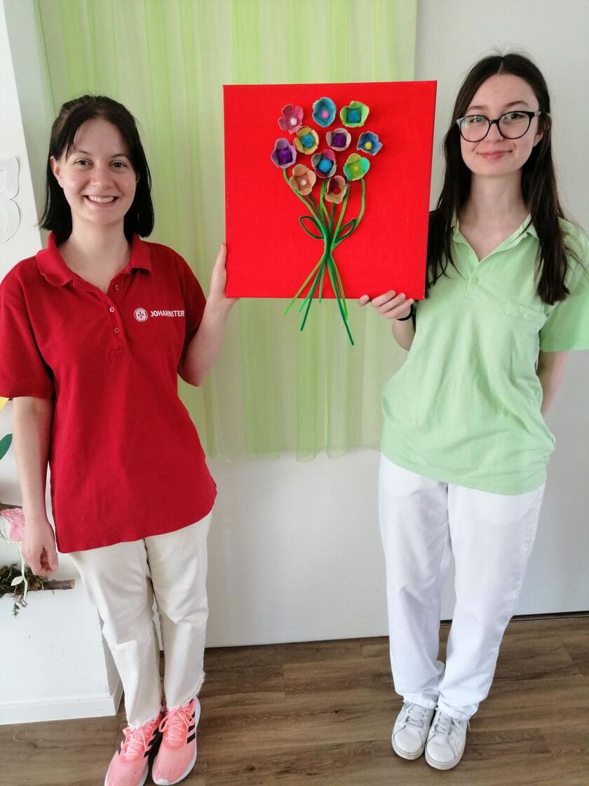 Zwei Frauen zeigen ein Bild mit Blume