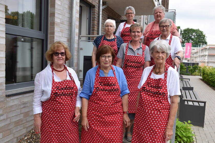Sieben Bewohnerinnen der Servicewohnen-Anlage und Hausdame Anja Paulmann stehen vor dem Gebäude. Alle tragen eine rote Schürze mit dem Aufdruck Kochclub Zirkusplatz