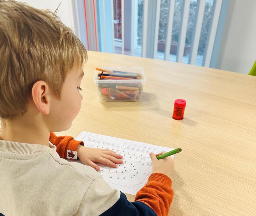 Ein Kind sitzt am Tisch und malt.