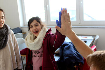 Ein Mädchen, das einen Einmal-Handschuh trägt, gibt ein High-Five