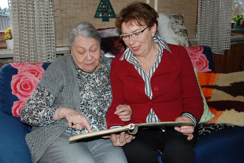 eine Besucherin schaut mit einer älteren Dame ein Fotoalbum an