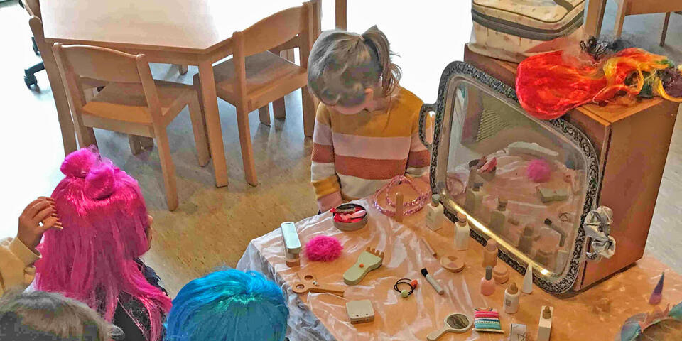 Kinder mit Perücken an einem selbstaufgebauten Friseurtisch