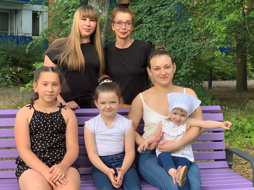 Eine Familie aus 6 Frauen und einem Baby, die auf einer Bank sitzen 