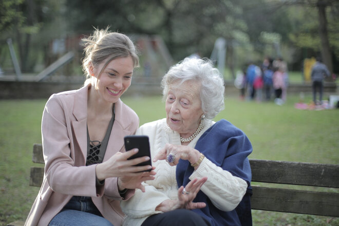 Eine junge und eine ältere Frau schauen gemeinsam auf ein Smartphone.