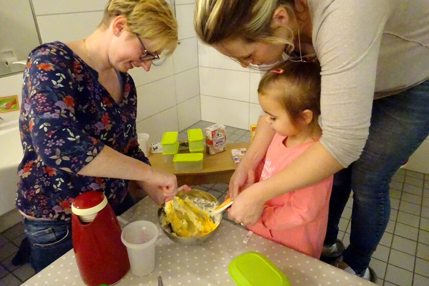Erzieherin, Mutter und Kita-Kind machen gemeinsam Kürbis-Kartoffel-Püree.
