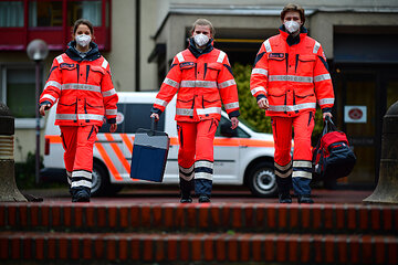 3 Mitarbeitende der Johanniter tragen FFP2-Masken und halten einen Container mit Impfstoff in der Hand.