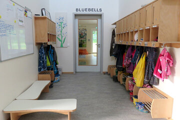 Zahlreiche kleine Jacken in bunten Farben hängen an den Hacken vor dem Gruppenraum der Bluebells. 