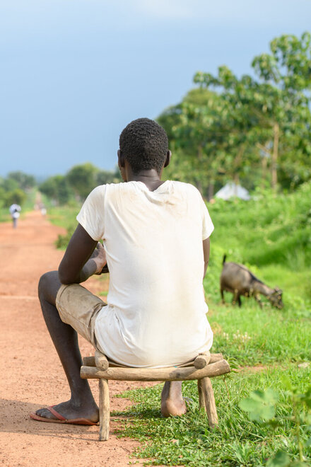 Lomuju sitzt auf einem Stuhl und schaut auf den langen Weg vor sich.