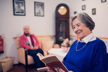 Eine Bewohnerin in blauem Pullover liest im Johanniter-Stift