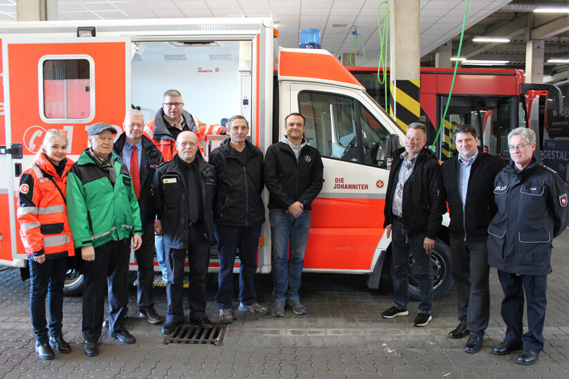 Mitarbeitende der Polizei Hildesheim, der Verkehrswacht, unserer Johannitern aus Hildesheim, dem ADAC und der Daimler AG stehen vor einem Rettungswagen. 