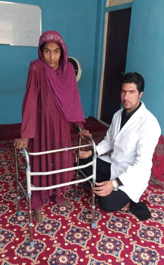 Eine Frau mit Behinderung erhält eine Gehhilfe von einem Johanniter Arzt