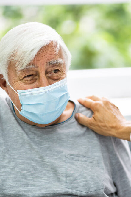 Ein älterer Mann mit einer medizinischen Atemmaske.