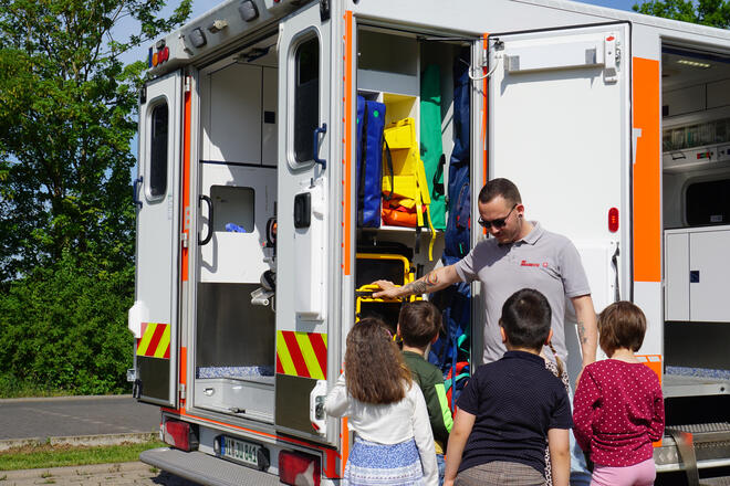 Ein Mann zeigt Kindern einen Rettungswagen