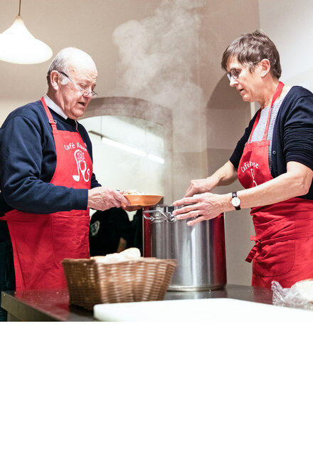 Freiwillige der Johanniter-Kältehilfe kochen Essen für Obdachlose.