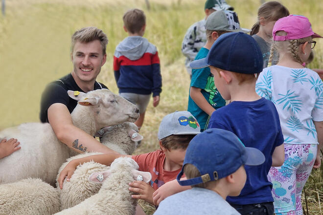 Ein junger Mann mit Kindern und Schafen