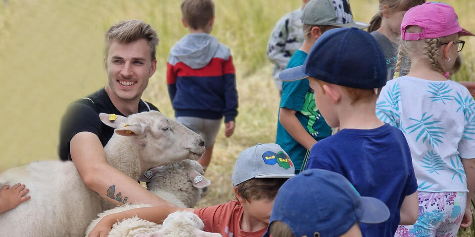 Ein junger Mann mit Kindern und Schafen