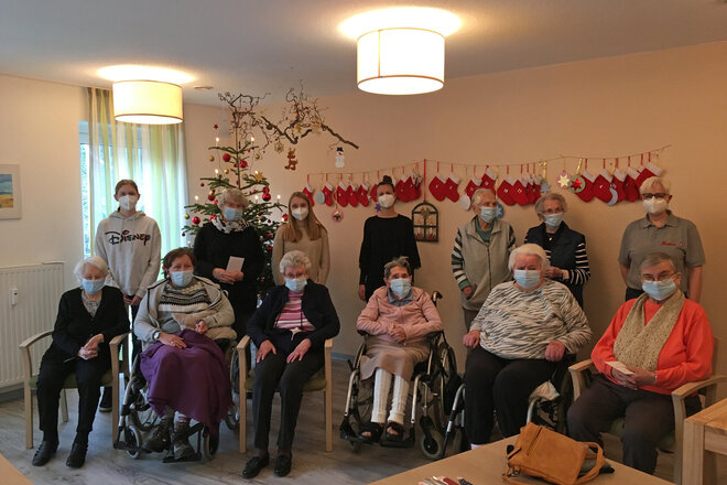 Gruppenbild mit Senioren, Mitarbeitern und Jugendlichen vor dem Weihnachtsbaum