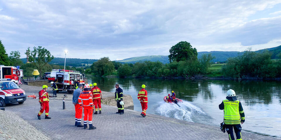 Einsatzkräfte von den Johannitern, der Feuerwehr und der DLRG am Ufer der Weser. Ein Rettungsboot ist zu sehen