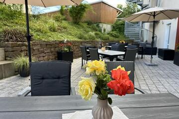 Eine Terrasse mit Stühlen, Tischen und Sonnenschirm