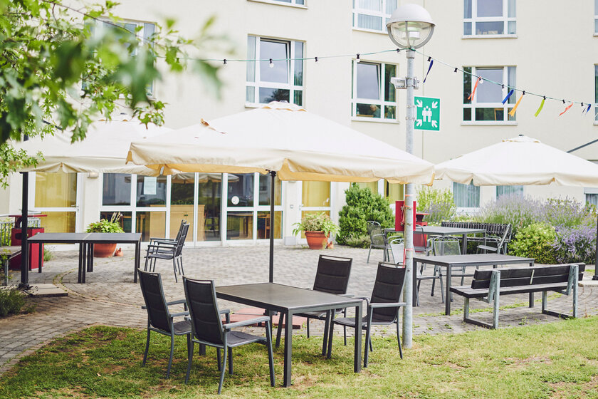 Tisch, Stühle und Sonnenschirme im Innenhof, Johanniter-Stift Duisburg