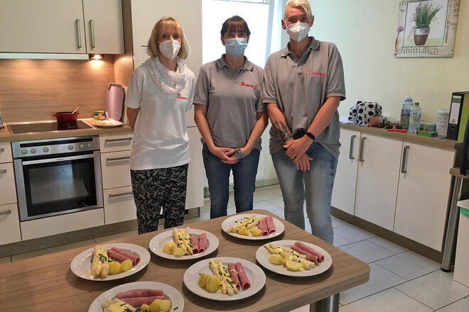 Drie Mitarbeiterinnen mit nett angerichteten Tellern mit Spargel und Schinken