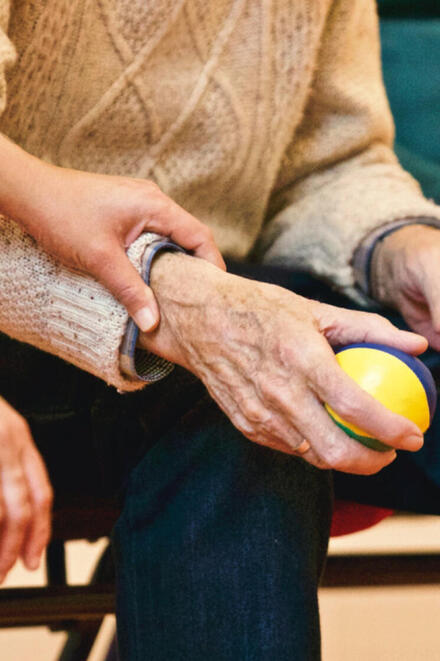 Eine ältere Person hält einen Jonglierball in der Hand.