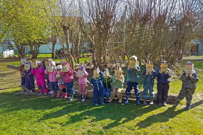 Kinder im Außengelände der Kita mit Ostertüten, die wie Hasen aussehen
