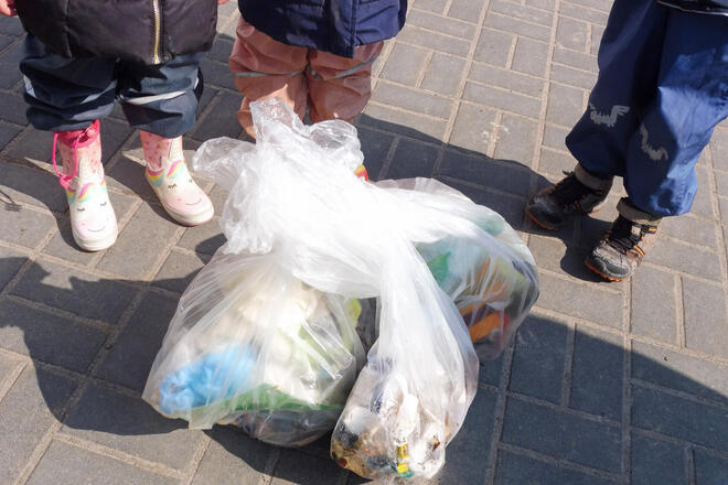 Kinderfüße neben Mülltüten