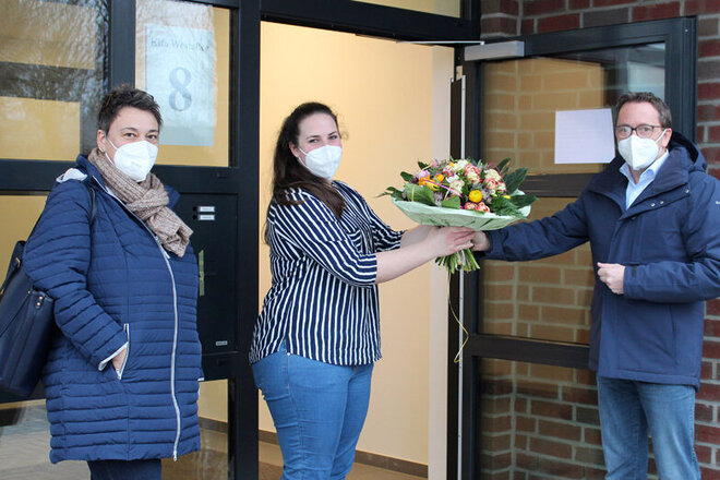 Die Kitaleitung erhält an der Haustür der Kita Westallee einem Blumenstrauß vom Bürgermeister der Samtgemeinde Leinebergland.