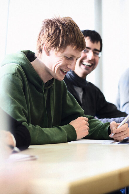 Zwei Männer lächelnd beim Lernen.
