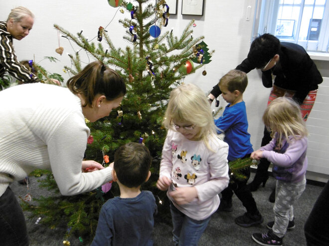 Kinder und Erwachsene dekorieren den Weihnachtsbaum liebevoll mit selbstgemachten Christbaumkugeln.