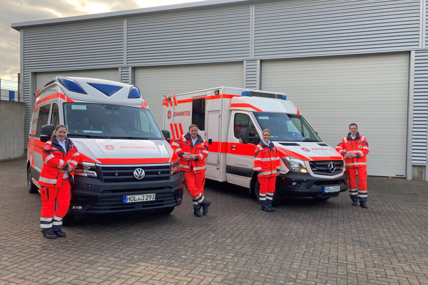 4 Rettungskräfte vor ihren Rettungswagen