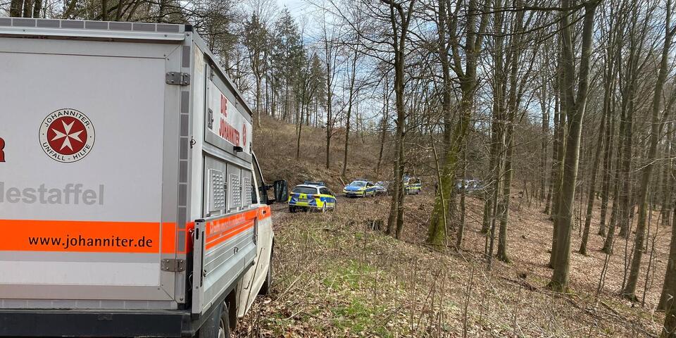 Polizei und Johanniter Fahrzeug parken an einem Waldweg