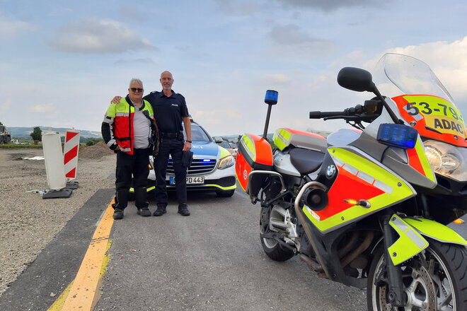 Ein Johanniter-Motorradstaffel-Mitglied und ein Polizist mit Krad und Einsatzwagen auf der Autobahn