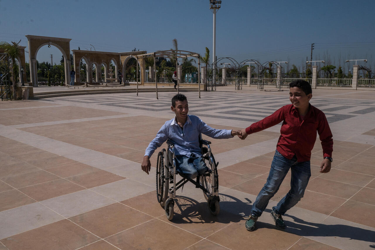Ein Junge spielt mit einem anderen Jungen der im Rollstuhl sitzt