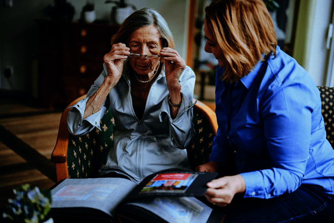 Eine ältere und eine jüngere Frau betrachten gemeinsam ein Fotoalbum