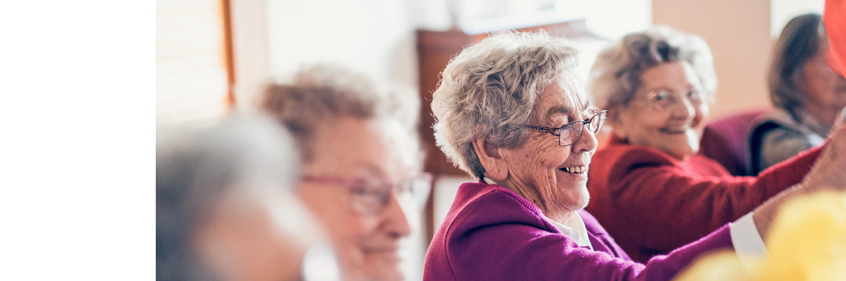 Eine lachende ältere Frau in einer Gruppe mit anderen älteren Frauen.